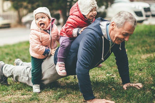 老人背着孙子做俯卧撑。