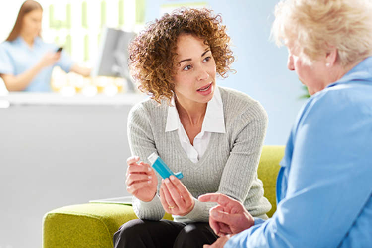 女士向长者讲解如何使用吸入器。