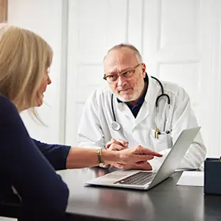 Woman talking to doctor, using laptop.