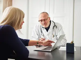 Woman talking to doctor, using laptop.