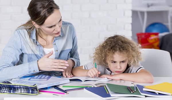 母亲帮助年幼的儿子解决家庭作业问题，难以集中注意力。