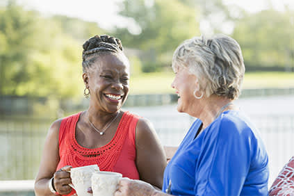 两位老年妇女在外面喝咖啡。