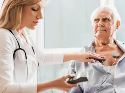 心脏病专家对老年男性病人进行心电图检查。