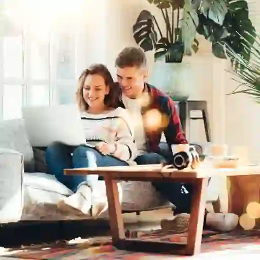 一对微笑的夫妇坐在沙发上，用笔记本电脑访问一个在线社区。