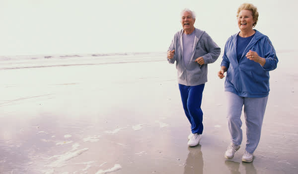 一对老年夫妇在海滩上慢跑