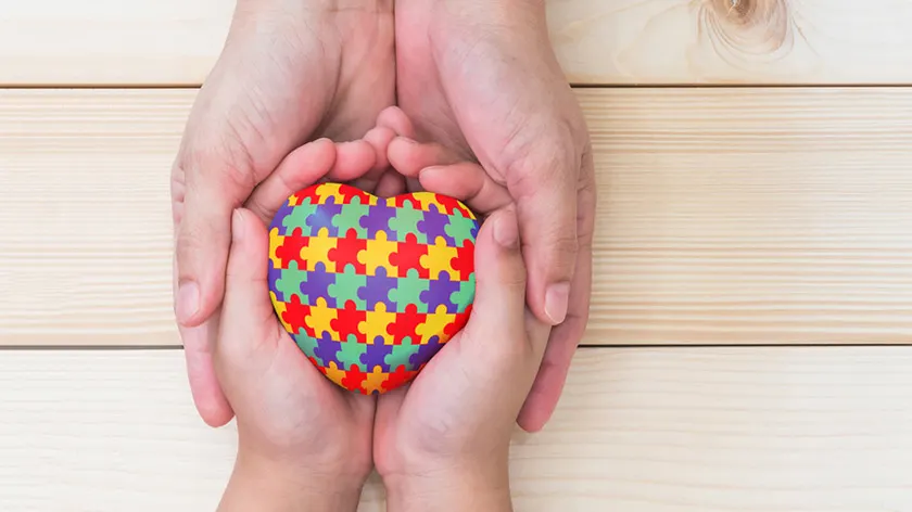 成人和儿童持有自闭症意识彩色心拼图。
