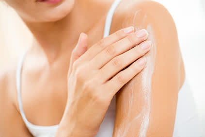 女人擦外用洗剂进她的皮肤。