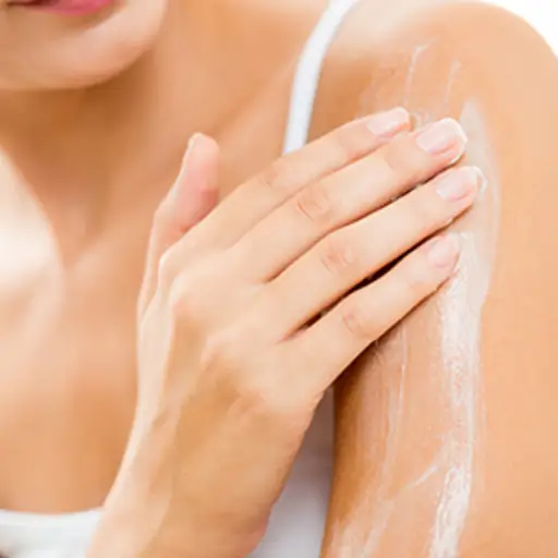 把局部洗剂擦进皮肤的妇女。