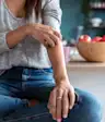 Woman with eczema scratching her arm.
