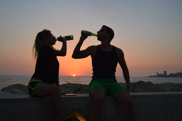 夫妇喝啤酒上海滩日落