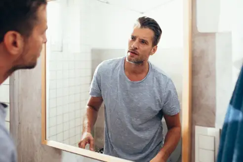 Man Checking Himself Out in a Bathroom Mirror