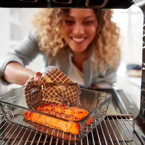 妇女烘烤鲑鱼在烤箱