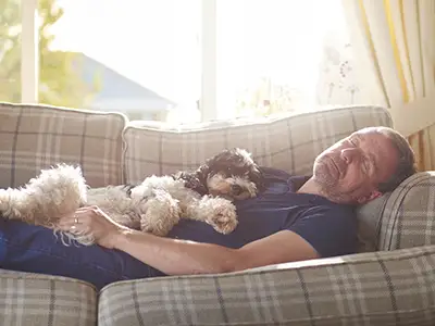 一个男人和他的狗在沙发上打盹。