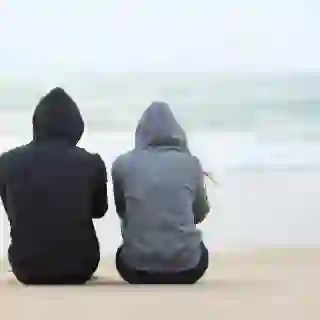 Man and Woman sitting solemnly at beach