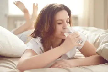 妇女饮用水在床上。