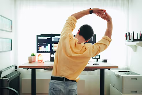 A man stretches at his desk