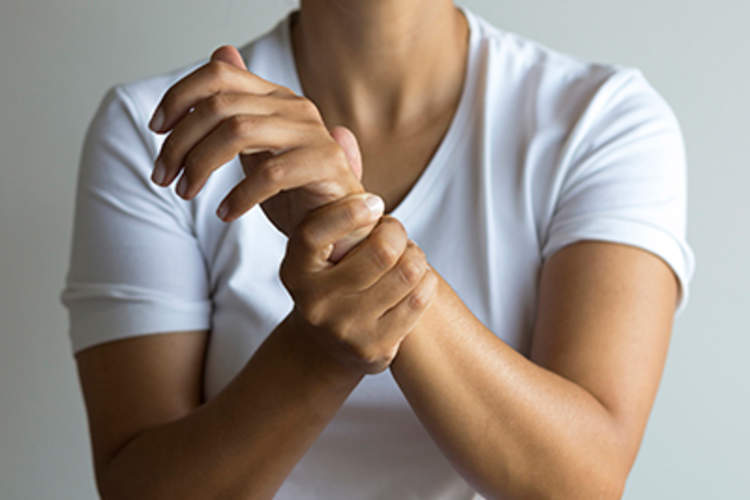 一个女人抱着她与RA关节疼痛的手腕。