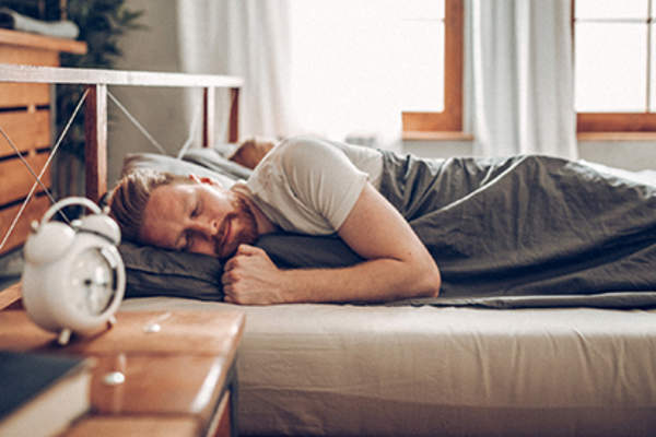 男子睡在床上靠近他的闹钟。