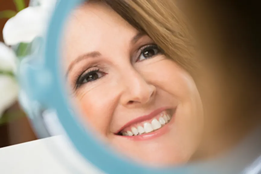 Happy mature woman looking in the mirror