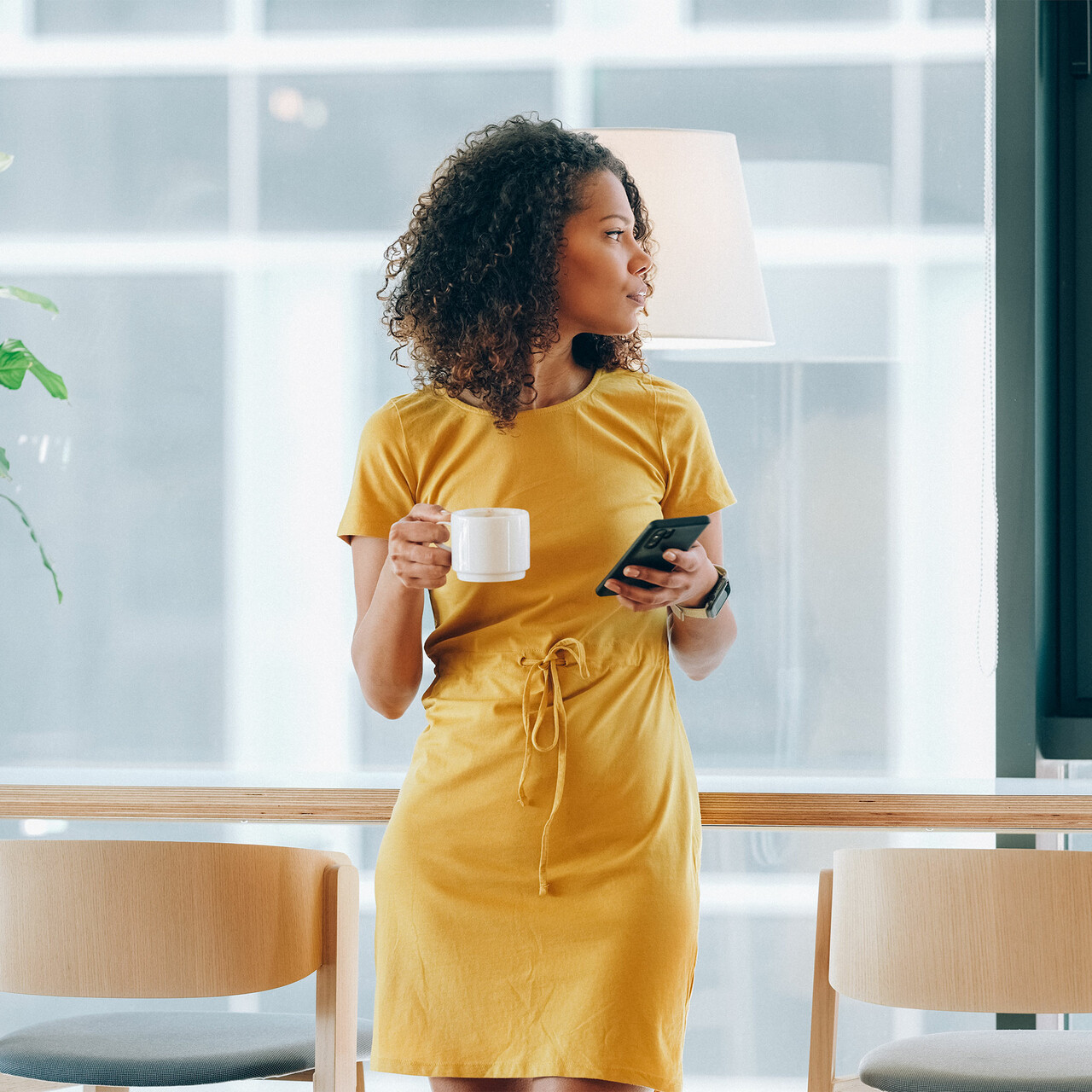 一位女士在办公室里端着咖啡杯