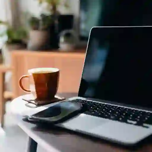桌上有笔记本电脑、手机和咖啡