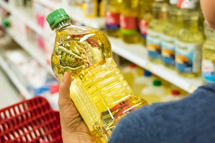 一个女人在商店里拿着一瓶食用油。