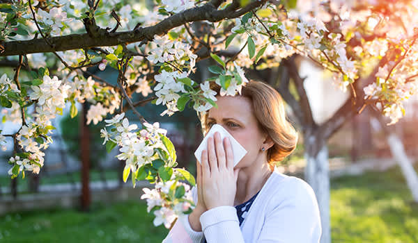 女人在户外吹她的鼻子，她从季节性过敏困扰。