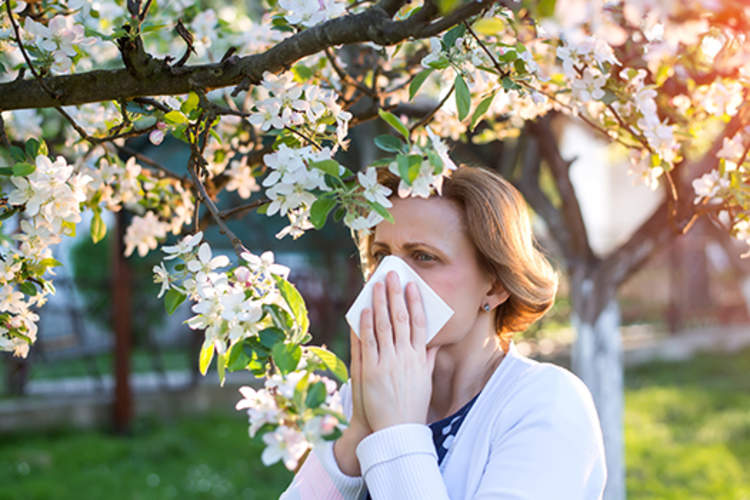 女人在户外吹她的鼻子,她从季节性过敏困扰。