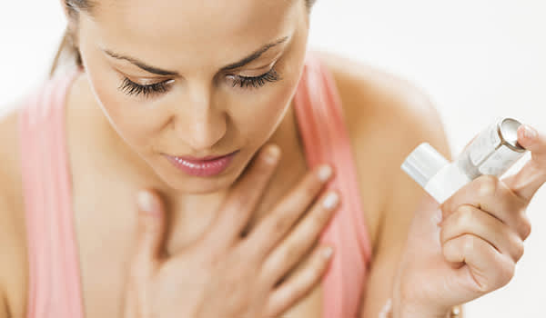 妇女使用吸入器治疗哮喘发作。