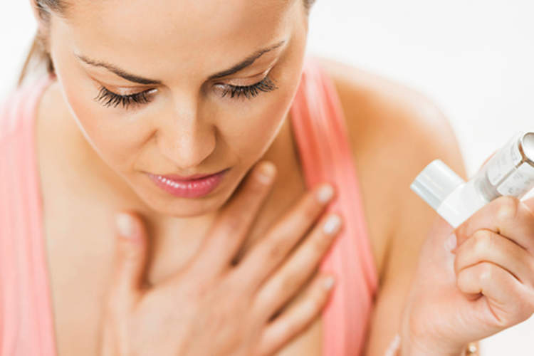 妇女使用吸入器治疗哮喘发作。