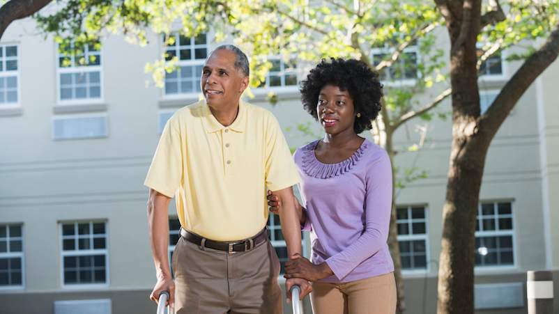 女儿走路,她的父亲为照顾者。