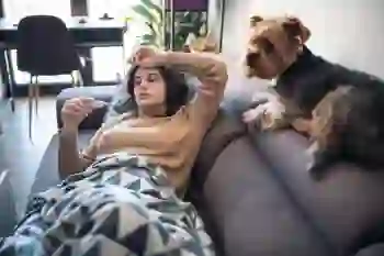 A sick woman lays on a couch at home with her dog