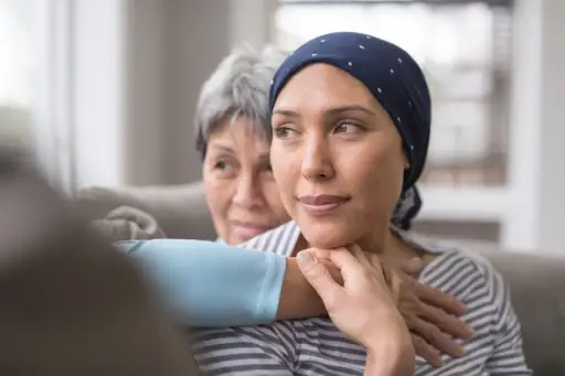 一位60多岁的妇女怀抱着她35多岁的女儿，她的女儿正在与癌症抗争