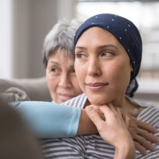 一位60多岁的妇女怀抱着她35多岁的女儿，她的女儿正在与癌症抗争
