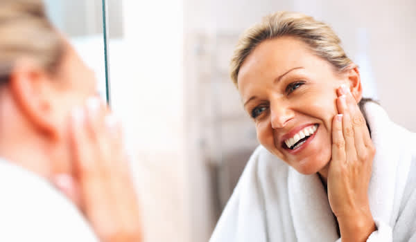 快乐的老妇人在镜子里检查皮肤。