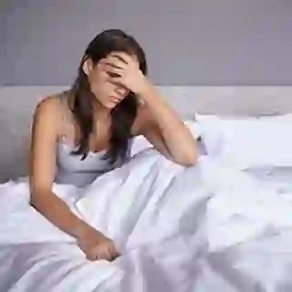 Woman in bed with a migraine.