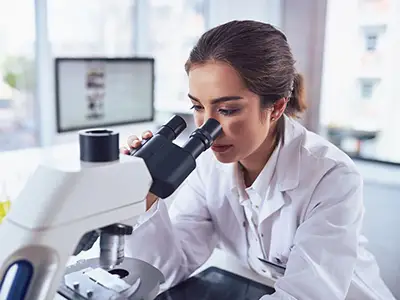 年轻女性病理学家在显微镜下观察。