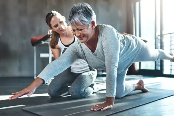年轻的女人在健身房帮助高级妇女