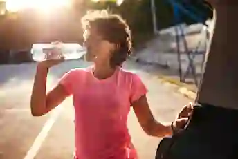 A woman drinks water while exercising outdoors