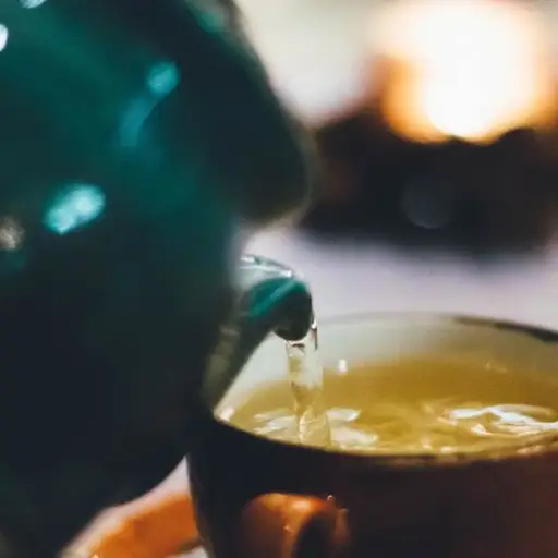 teapot pouring green tea into cup