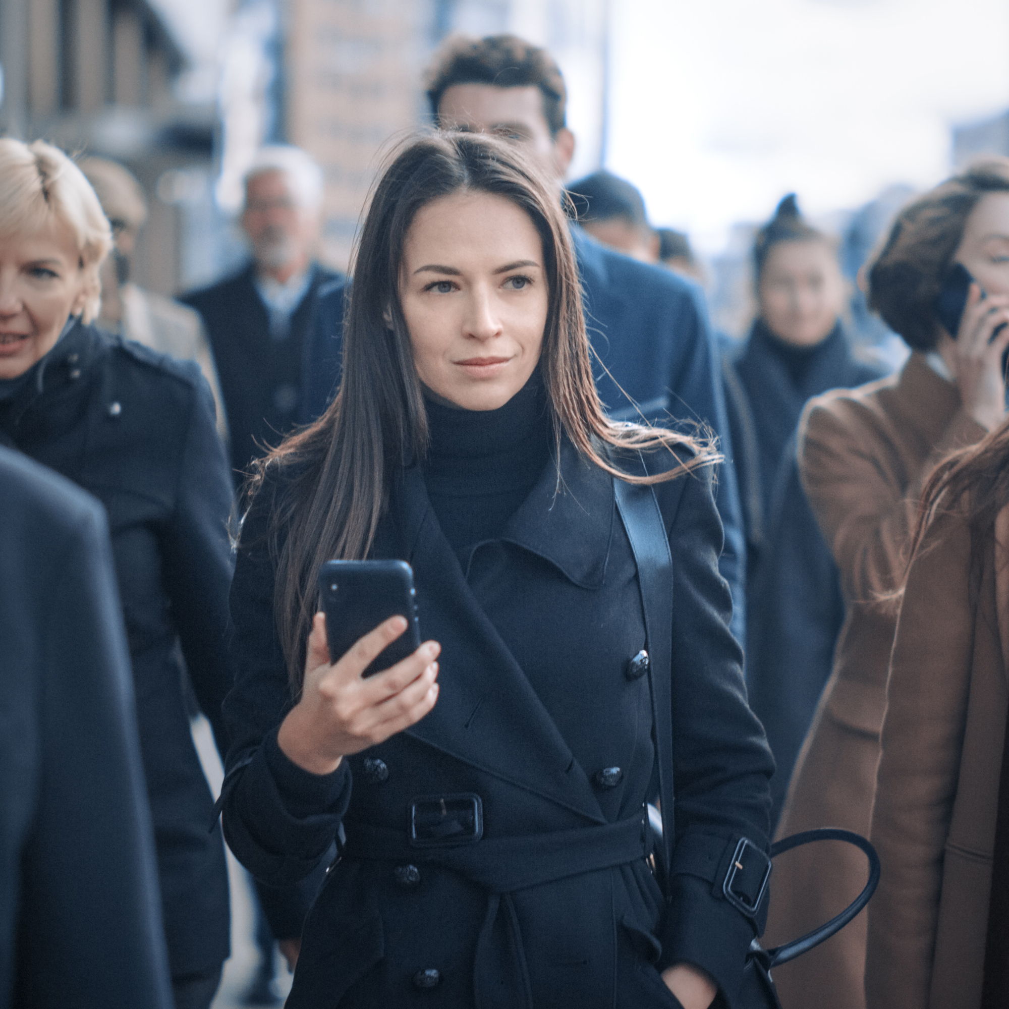女人的电话在人群中一个城市人行道上。