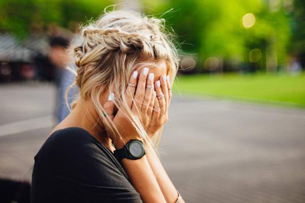 害羞的女人躲在脸,手