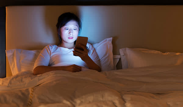 女人在床上使用智能手机