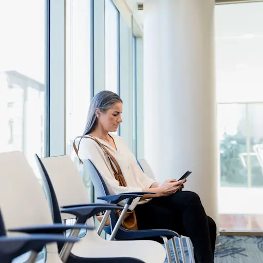 一个女人在医院的候诊室里看着她的手机