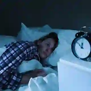 Sleepless Young Woman with Insomnia in Bed, Watching Alarm Clock