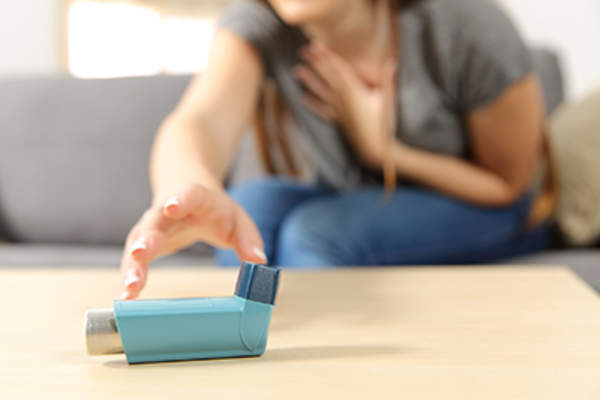 女孩哮喘病发作了,正在拿呼吸器。