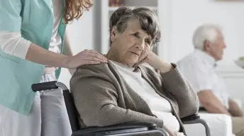 老年痴呆妇女坐在轮椅上，感到无助。