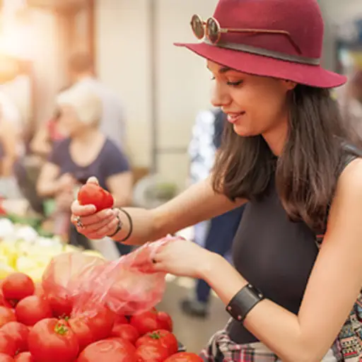 看蕃茄的妇女在一个室外市场上。