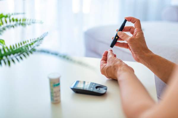 女人坐在沙发上用血糖仪检查血糖水平