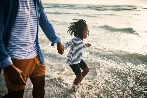 Parent and child walking along the beach